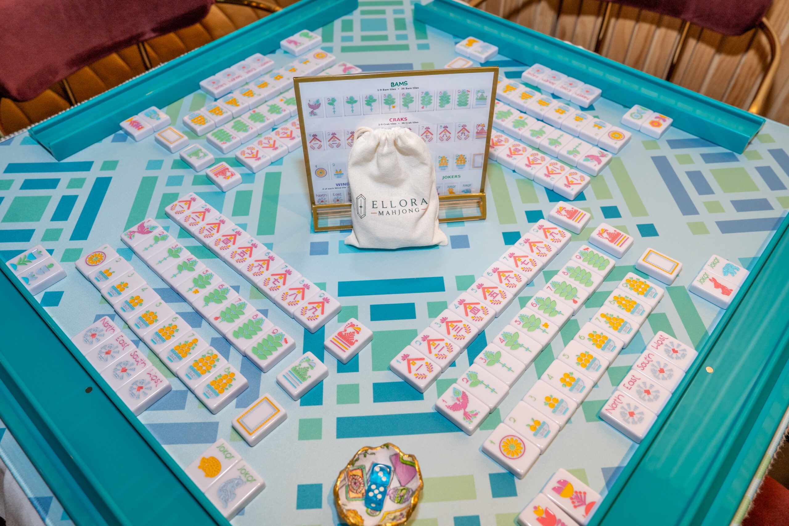Colorful American mahjong set with Ellora Mahjong branded tile bag in center.